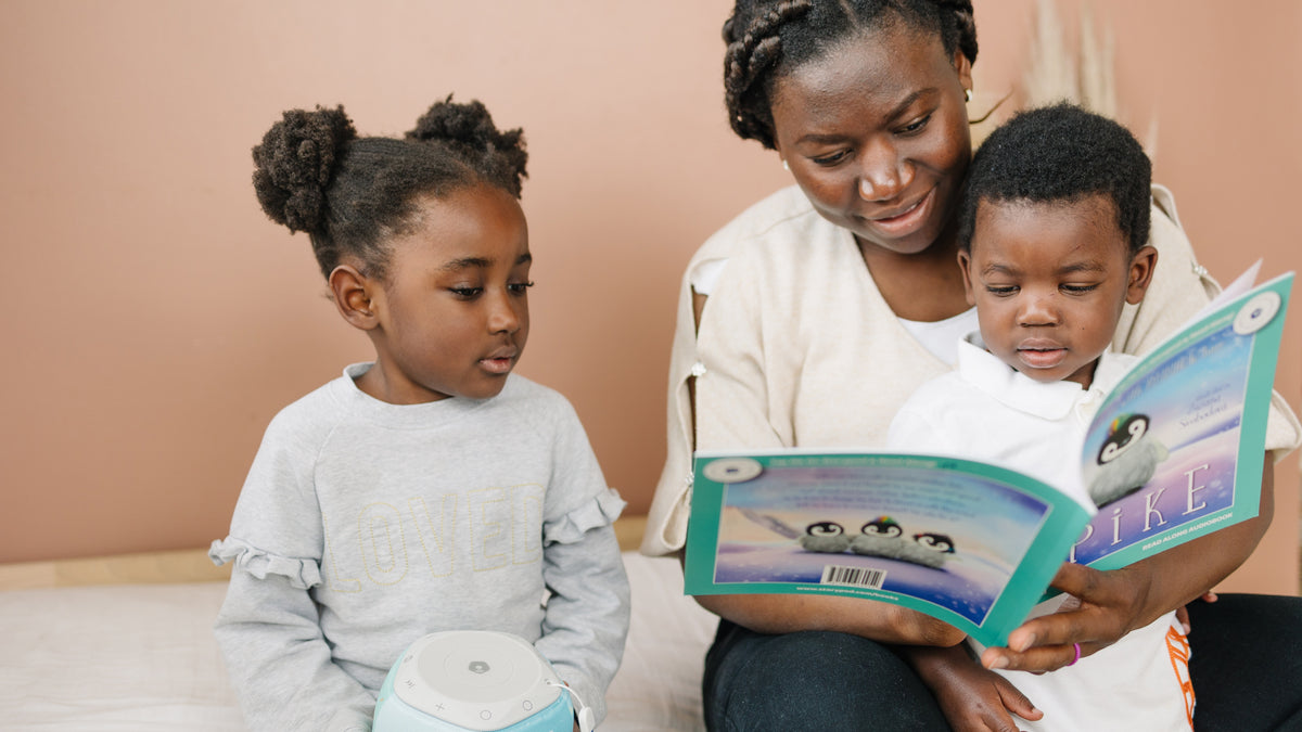 A mom reads the Spike audiobook with her young son while her daughter holds a Storypod