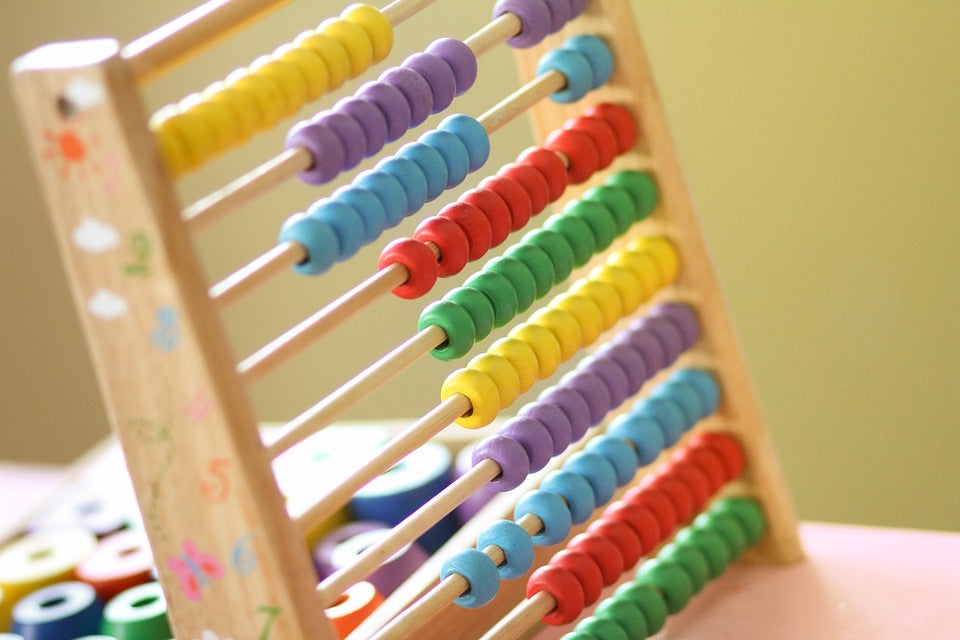 A colorful children's abacus sits on a table. There are many fun ways to practice addition and subtraction with your kindergartener.