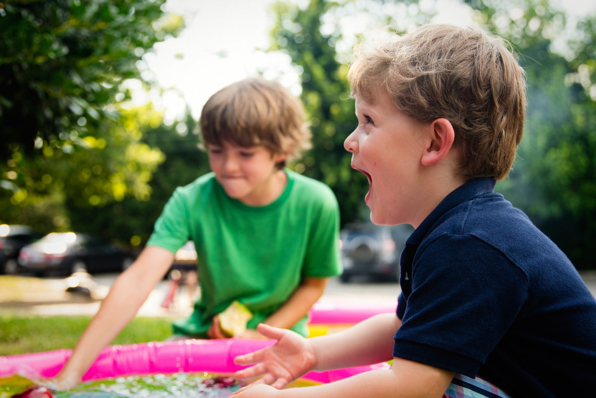 Two kindergarten-aged boys happily take turns using toys.