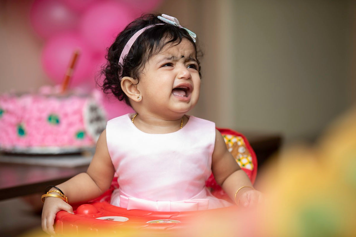 1-year-old girl in a pink party dress cries out for Mom and Dad. Children can develop separation anxiety as early as 4-5 months and can last to 3 years of age, if not managed properly.