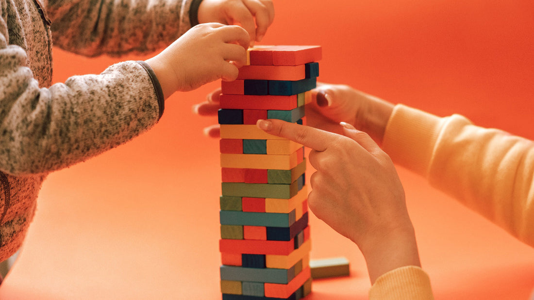 Child and mother's hands play a game of Jenga indicating bonding