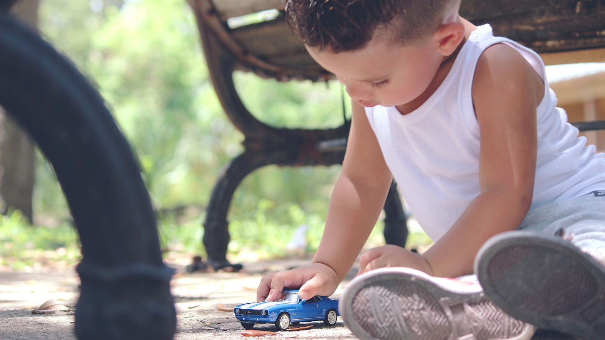 Toddler peacefully plays with toy  car independently