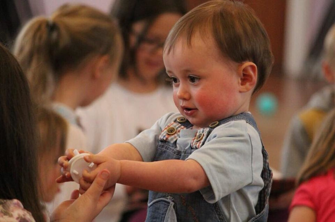 2-year-old boy offers another child a toy. Although toddlers are not quite ready to play cooperatively with other children, then can begin to practice positive social interactions with other children their age.