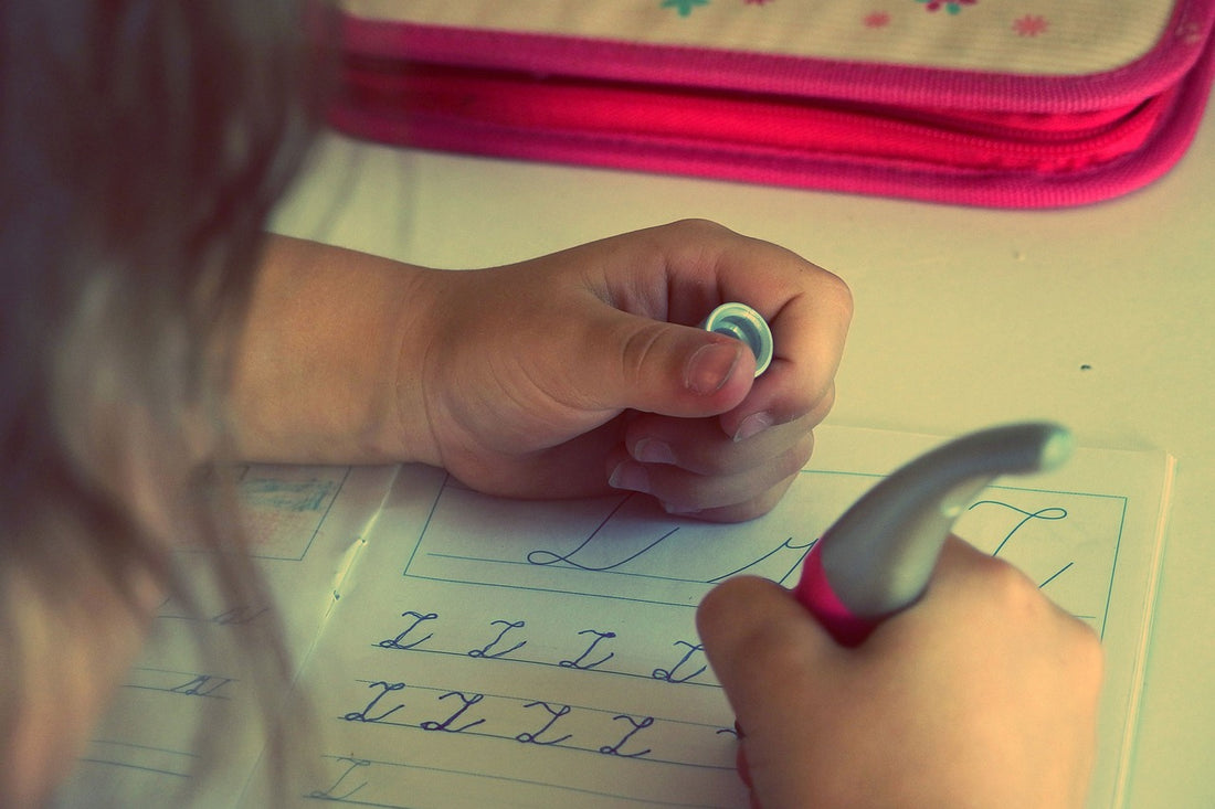 4-year-old girl traces her letters in a workbook. Tracing can be educational for children at this age, especially when it comes to letter formation.