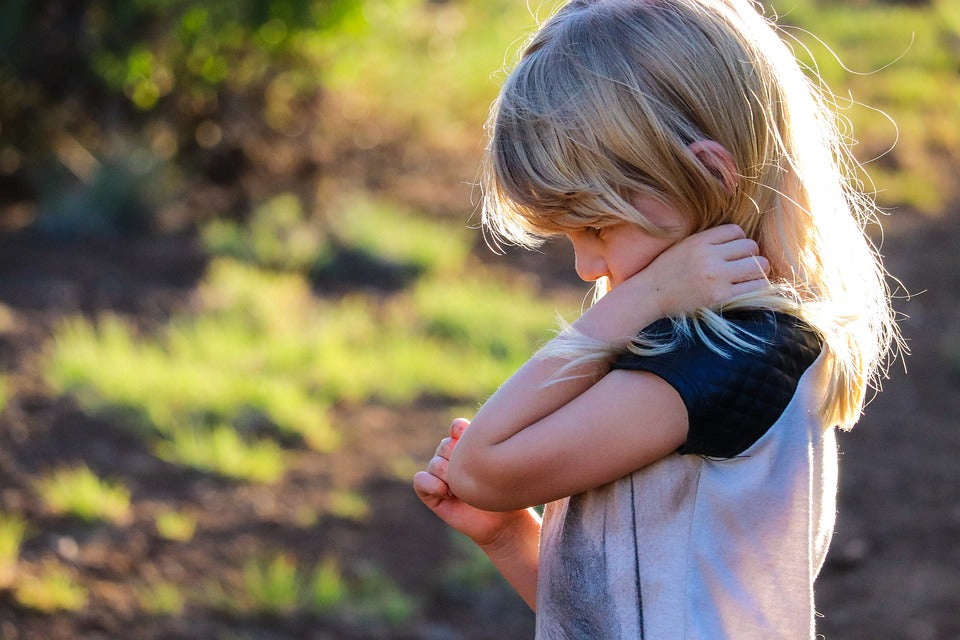 A 4-year-old girl holds her elbow with a forlorn expression. Teaching children at this age to identify their emotions is important for self-regulation and learning to sympathize with others.