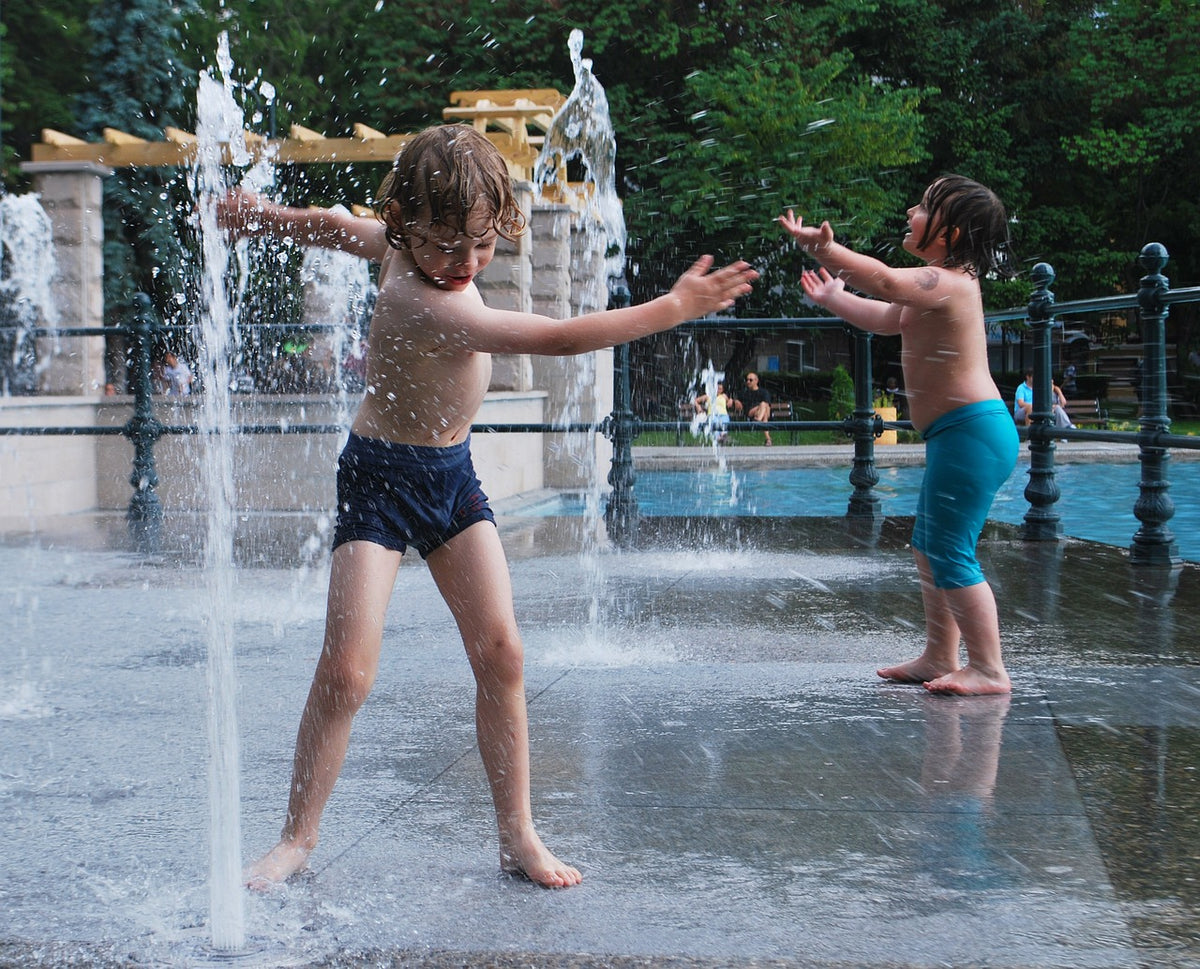 A pair of boys play with an outdoor water fountain in their swimming trunks. At 5-years-old, your child is ready to play outside with more independence. Just be sure to consider safety factors before sending your child to go play alone.