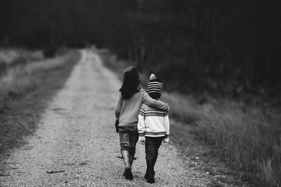 A young boy and girl walk down a trail with their arms around each others' shoulders. Teaching your child about what friendship should feel like will help them have healthy boundaries and positive social interactions.