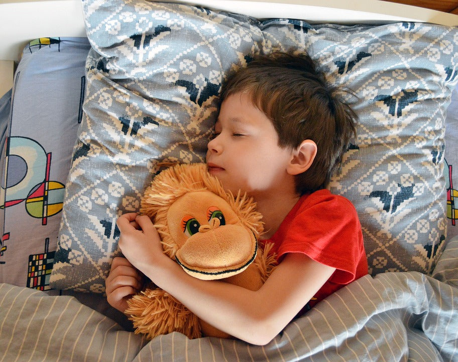 5-year-old boy cuddles with his favorite stuffed monkey as he drifts off to sleep. Having a good bedtime routine is vital to ensuring a quality night of rest and a productive morning the next day.