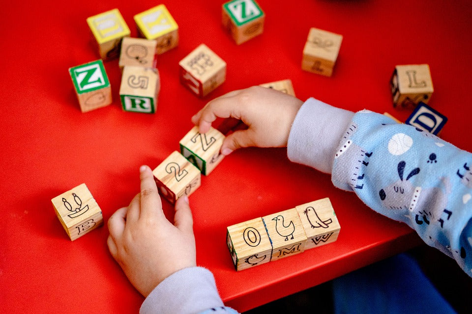 A pair of child's hands plays with a set of square blocks. At 3-years-old, your child will begin to recognize and sort shapes.