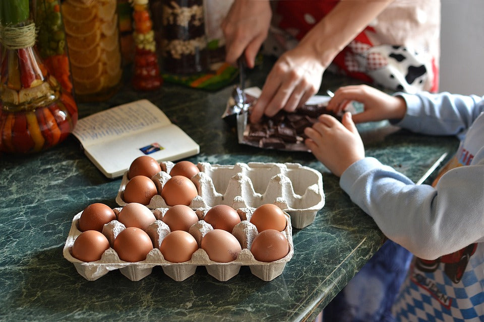 A mother's hands chops up chocolate as her 4-year-old assists. Doing activities together in the kitchen can be a fun and educational experience.