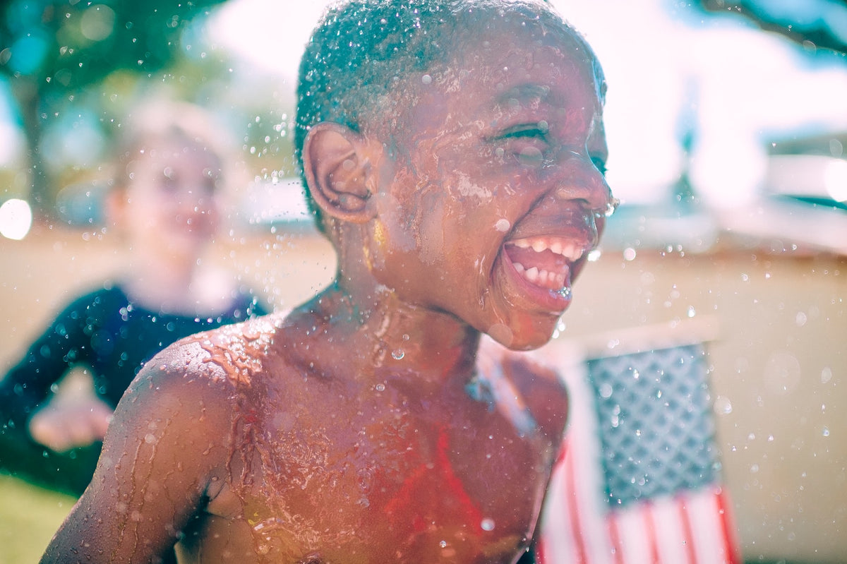 Five-year-old boy runs gleefully through the water, sporting a big smile. There is lots to look forward to when your child turns 5.