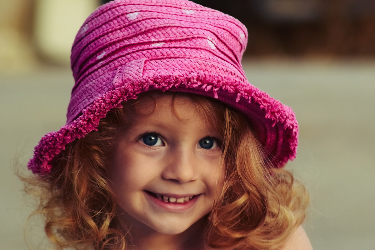 6-year-old girl with a pink hat smiles. Raising a child with strong coping skills will create a happy and resilient adult in the future.