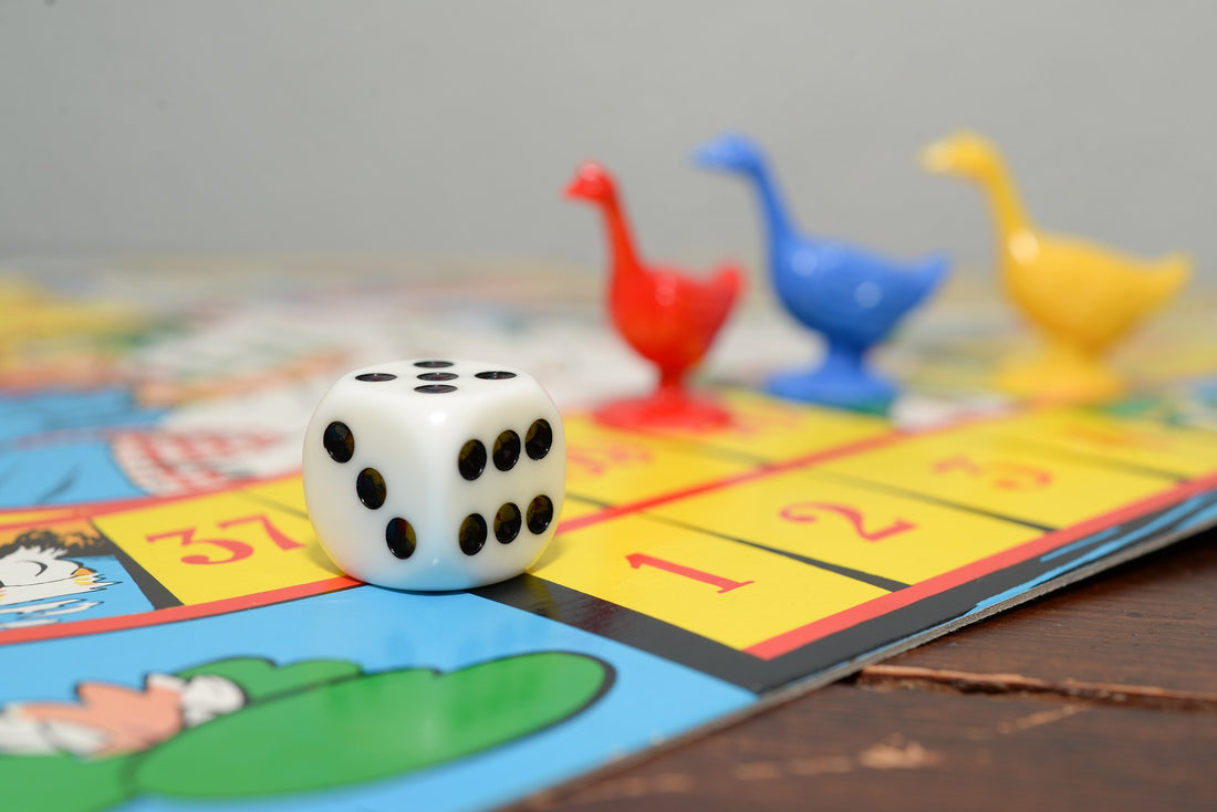 Dice and colored goose figurines lay atop a colorful board game. At 4 years of age, your child is ready for age-appropriate board games that the whole family can enjoy.