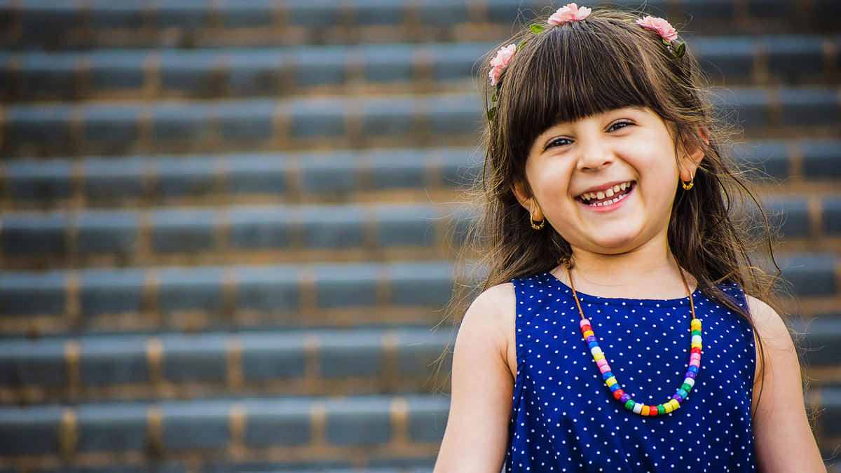 Young girl smiling with a blue shirt and necklace