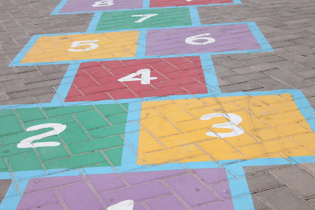 A game of hopscotch is etched in chalk on the pavement. Hopscotch is an easy backyard game you can play to help promote your 4-year-old's motor skill development.