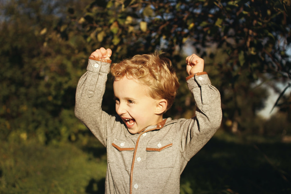 Smiling 4-year-old boy raises his hands in excitement. There are many ways to manage over-excitement when big events are on the horizon.