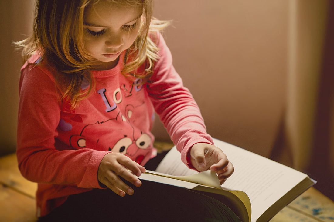 Little girl quietly reads a book on her lap. There are 4 predominant learning styles that children may gravitate toward. Parents should make an effort to find out and understand their child's learning style.