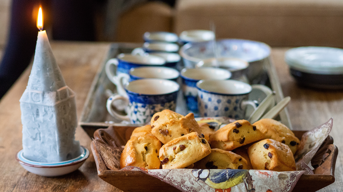 Scones, teacups, and a holiday candle sit atop a wooden table.