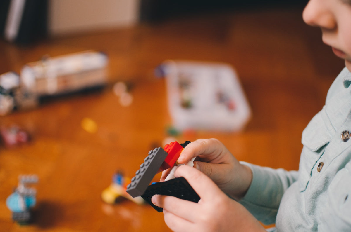 A pair of child's hands build an imaginary apparatus with Legos. Imaginative play is crucial for a 4-year-old's development.