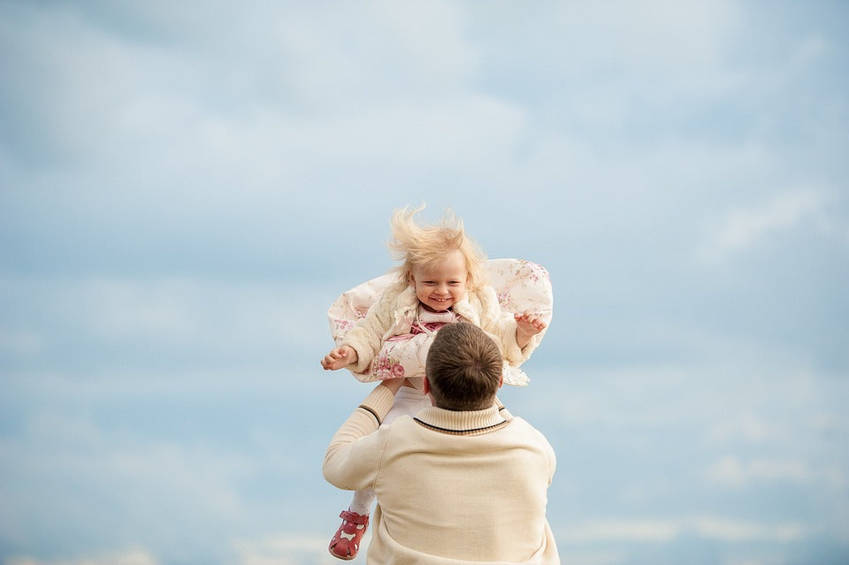A father gleefully tosses his 3-year-old daughter in the air. Creating a safe a nurturing environment is one way to build honesty in your little one at this age.