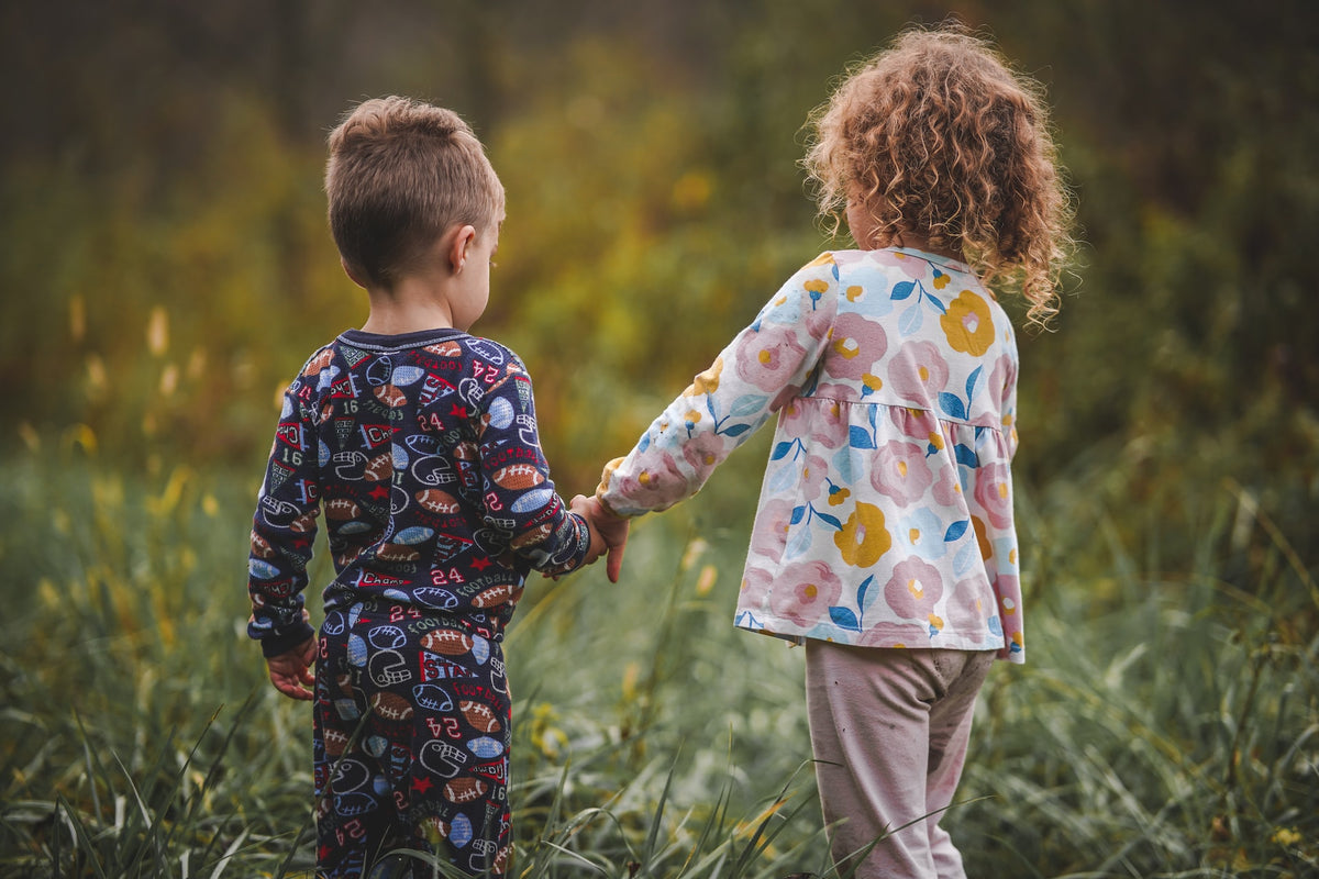 A toddler and a young child hold hands while walking through a field. Turn taking a crucial social skill that you will want to begin instilling in your child as early as possible.