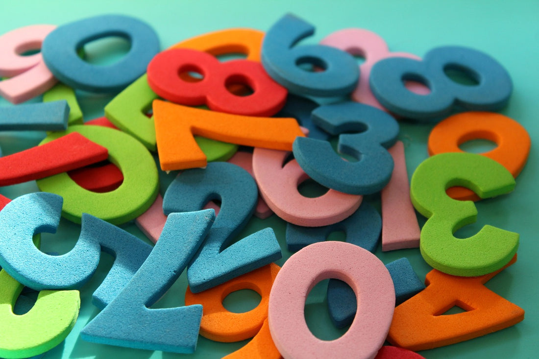 A pile of colored foam numbers lie on a blue table top. Using manipulatives in one strategy you can use while practicing addition and subtraction concepts with your 6-year-old.