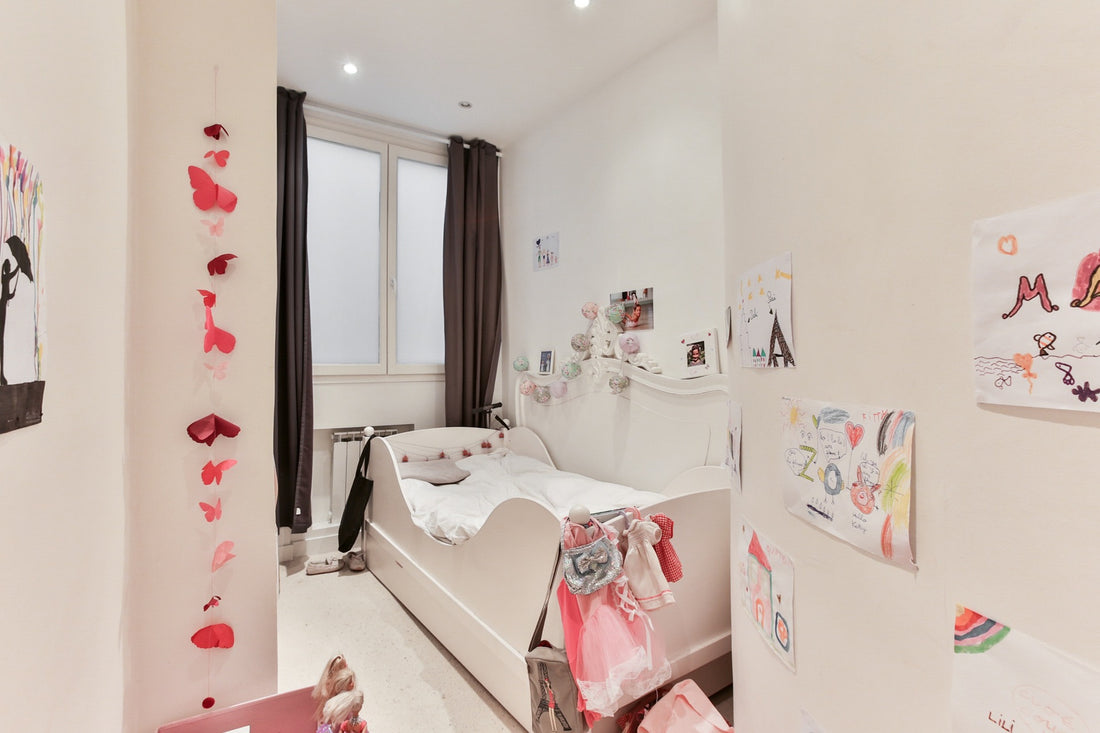 A little girl's bedroom contains a bed and plenty of displayed children's art. Your 5-year-old's bedroom should be functional, tidy, and have plenty of space for play and creativity.