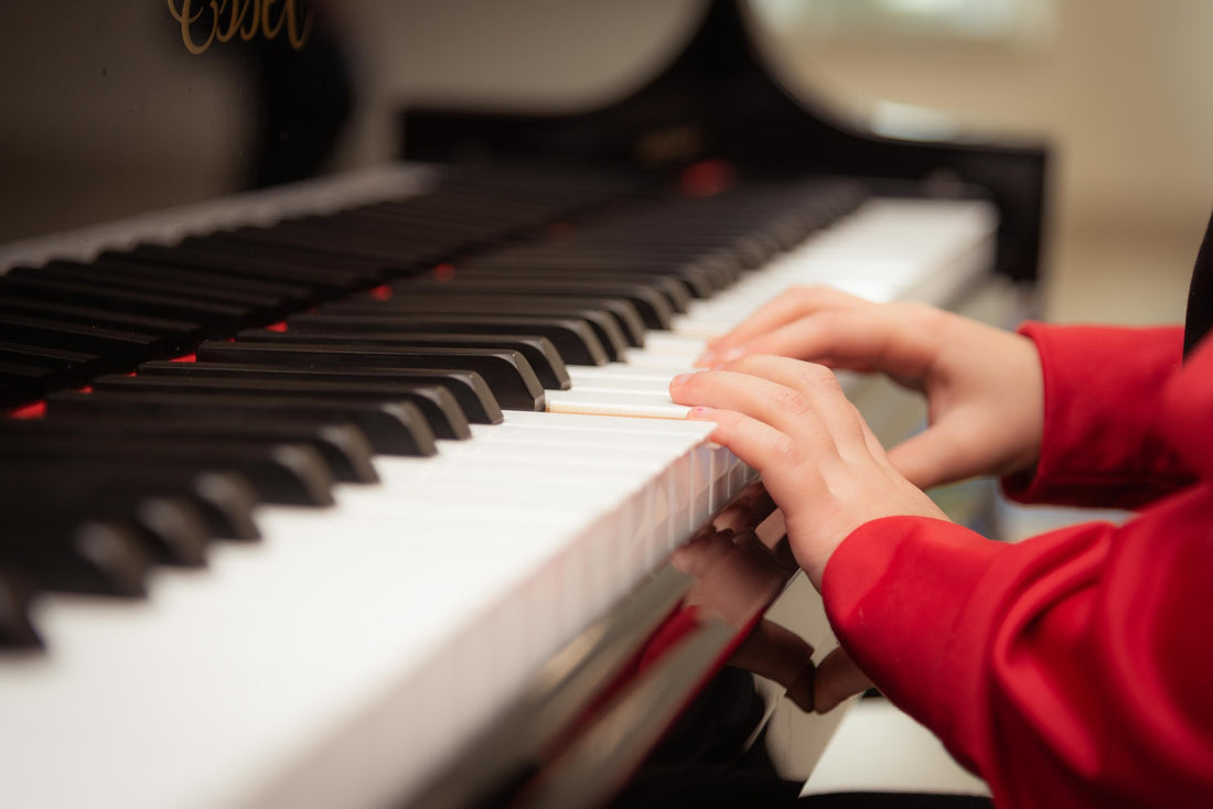 A pair of child's hands tinker on a piano keyboard. Music is a great educational tool and benefits child development in many ways.