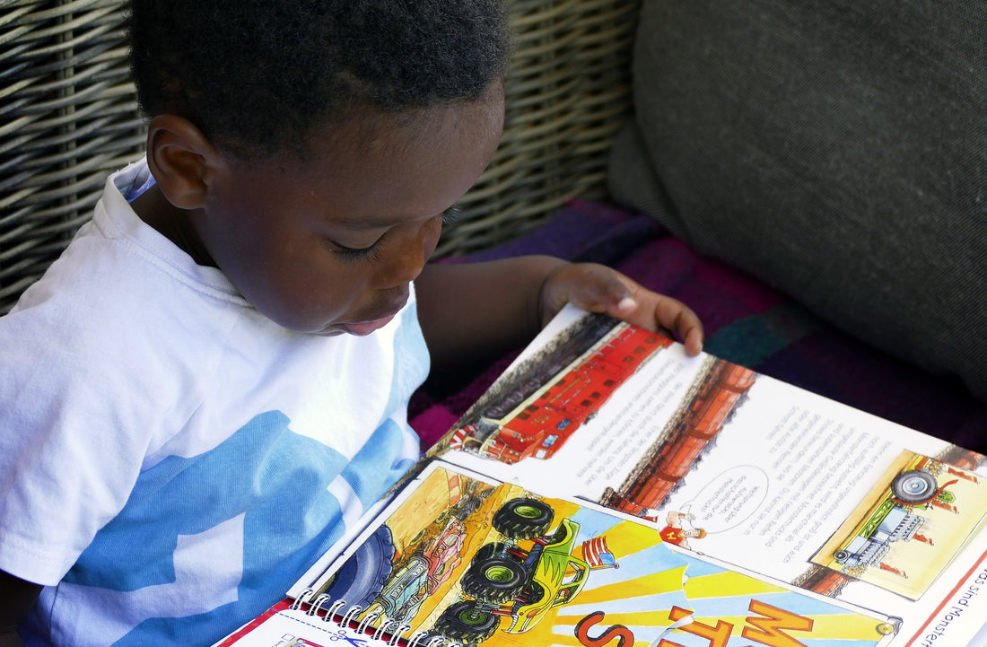 6-year-old boy reads a book on his lap. Children at this age should be reading regularly each day.