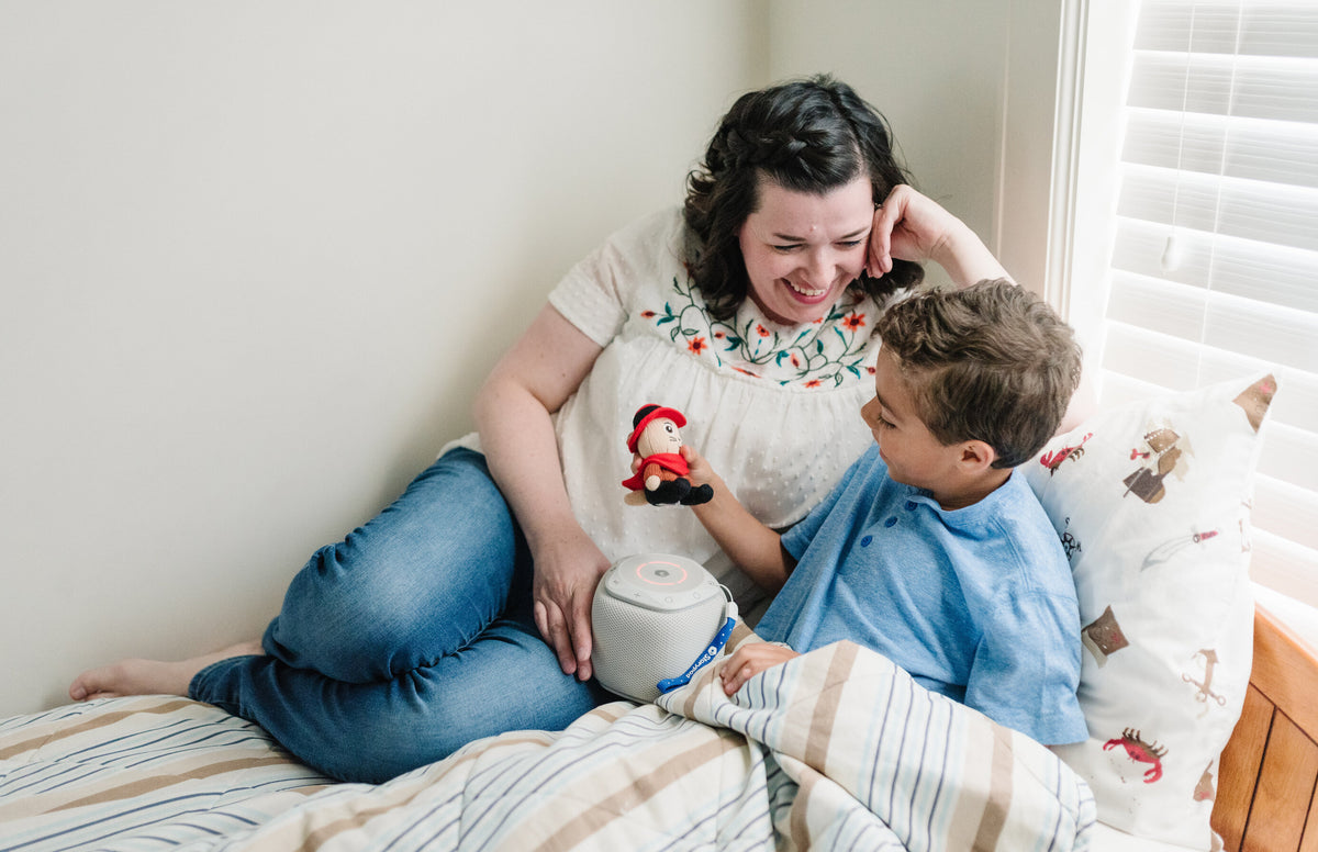 Mother converses in the bed with her 4-year-old son, who is holding a Storypod and Puss in Boots Craftie. Having regular conversations with your 4-year-old is important for their language and social development.