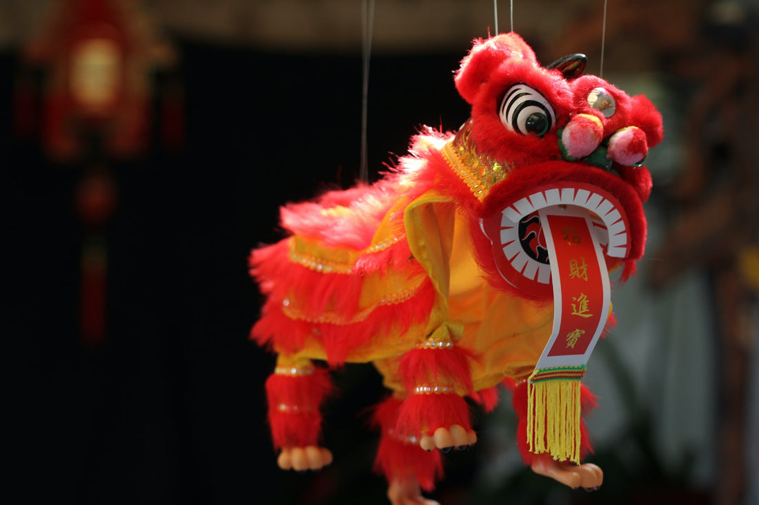 A red and gold Chinese toy dragon hangs, suspended on strings. Dragons represent good luck, strength, and health in Chinese culture and is one of the common symbols seen on Chinese New Year.