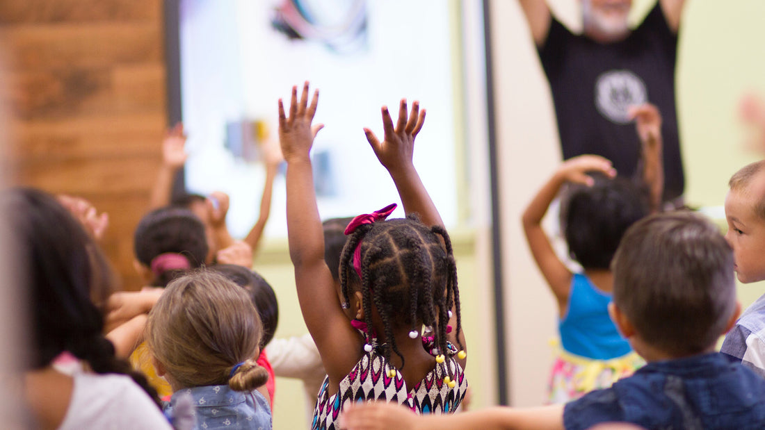 Kindergarteners raise their hands in the classroom