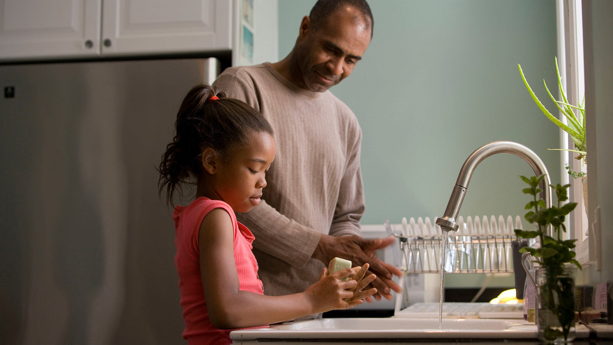 Father and daughter clean dishes together as a part of their cleaning routine