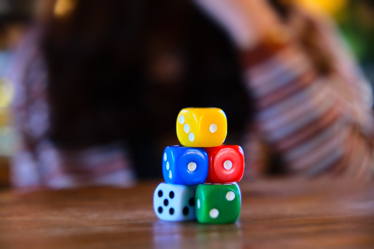 A stack of colorful dice lay on a table. Using the "roll & retell" method is a fun way for your child to practice reading comprehension after reading a story.